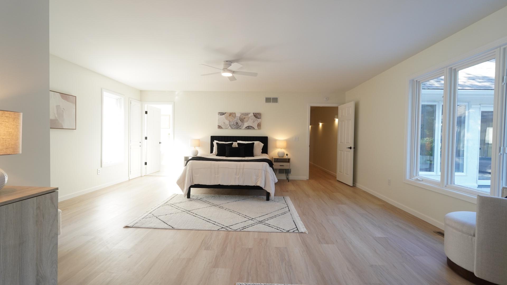 The spacious, light and airy primary suite features a fully remodeled en-suite bath, a large closet with a custom closet system, a separate wash tower enclosed in a closet, and direct access to both the pool and patio.