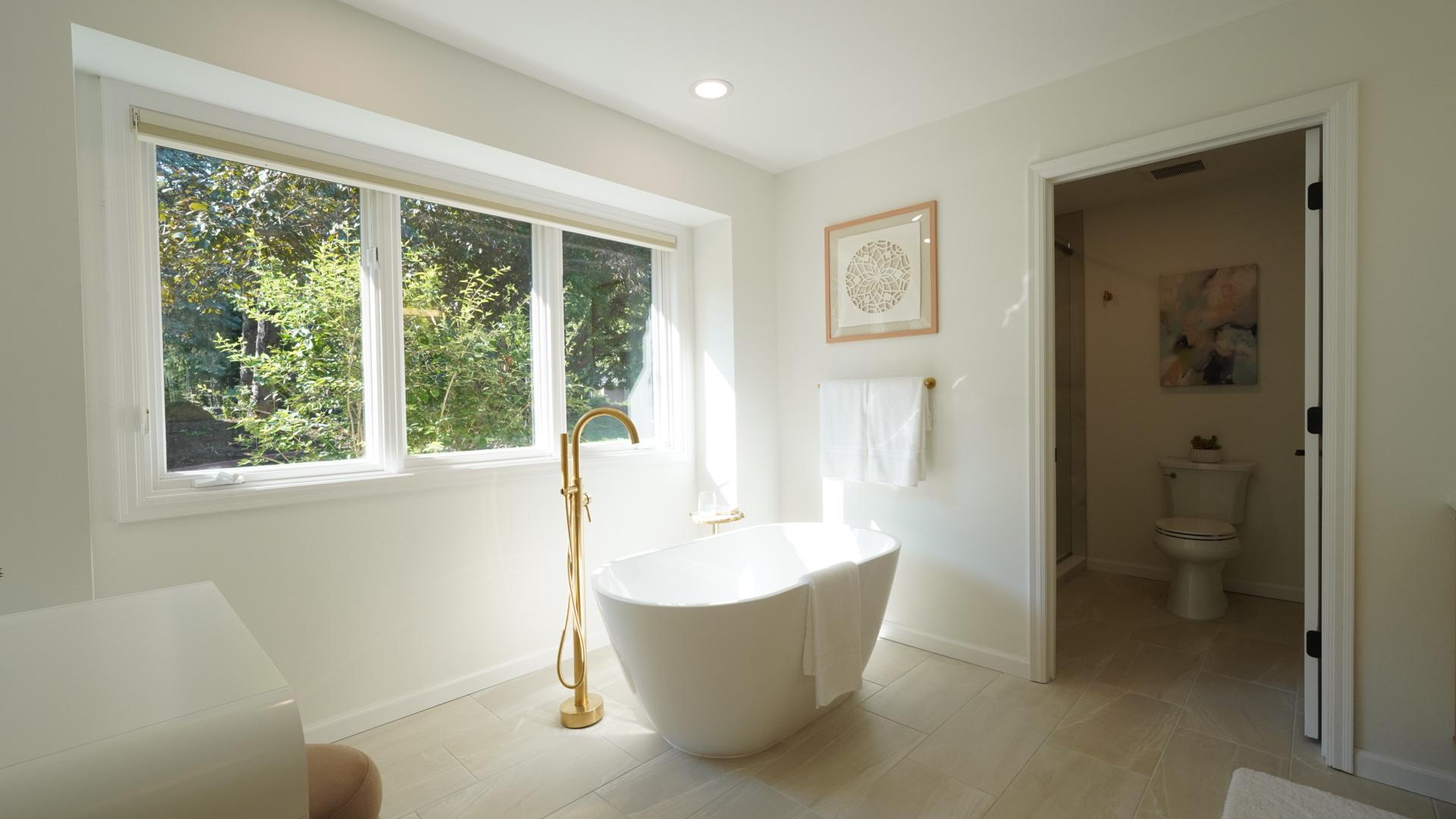 The generous main room of the primary bath is filled with natural light which highlights the spacious, freestanding tub.