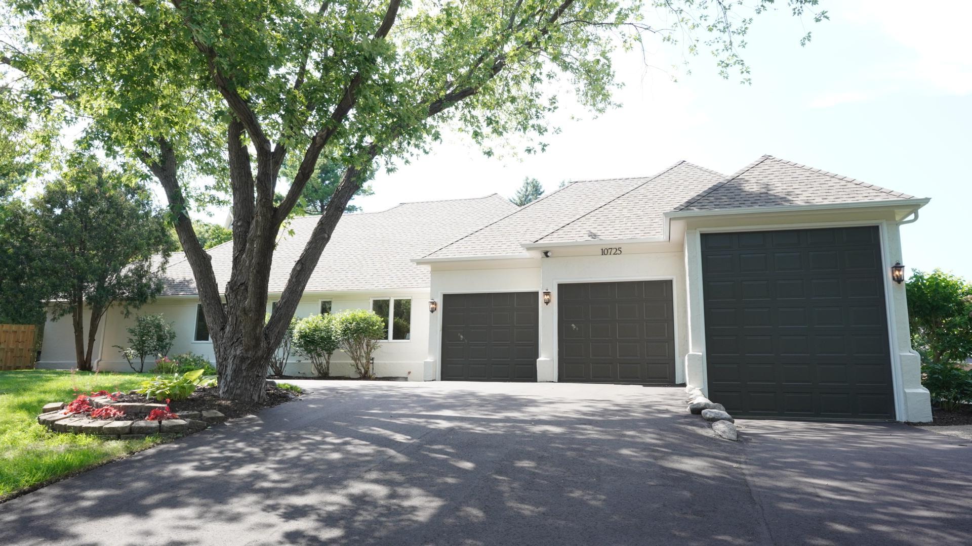 The staggered garage doors add visual interest. The third garage stall is wider and taller than usual to accommodate a boat or RV. The oversized driveway has been newly paved, and new exterior lights flank the freshly painted garage doors.