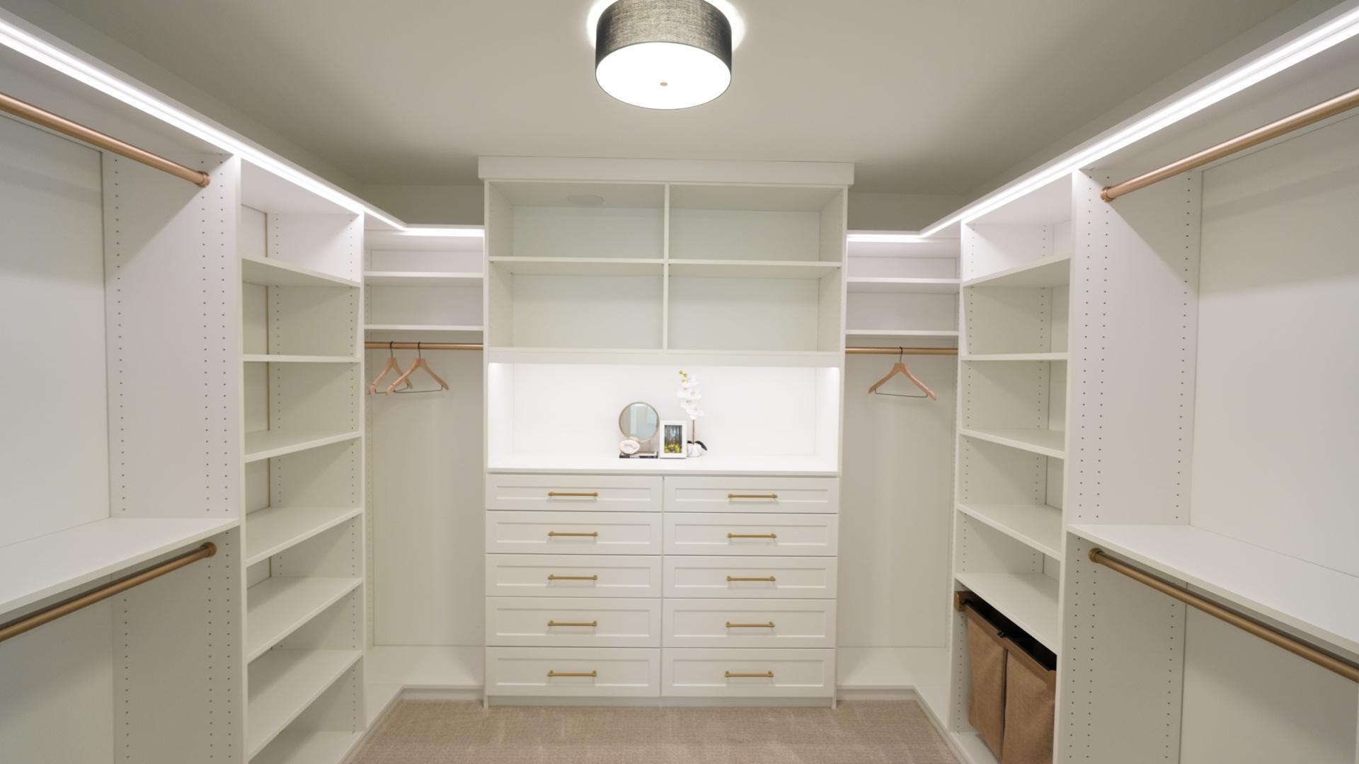 Minimize your need for dressers with this versitile, highly customized primary bedroom closet system which features integrated indirect lighting, two clothes hampers, and a wide array of drawers, hanging areas, and open storage.