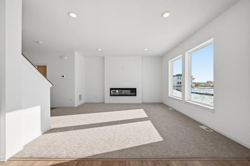 The main living space is bright and welcoming, featuring large windows that bring in abundant natural light. Images of similar home, interior selections differ.