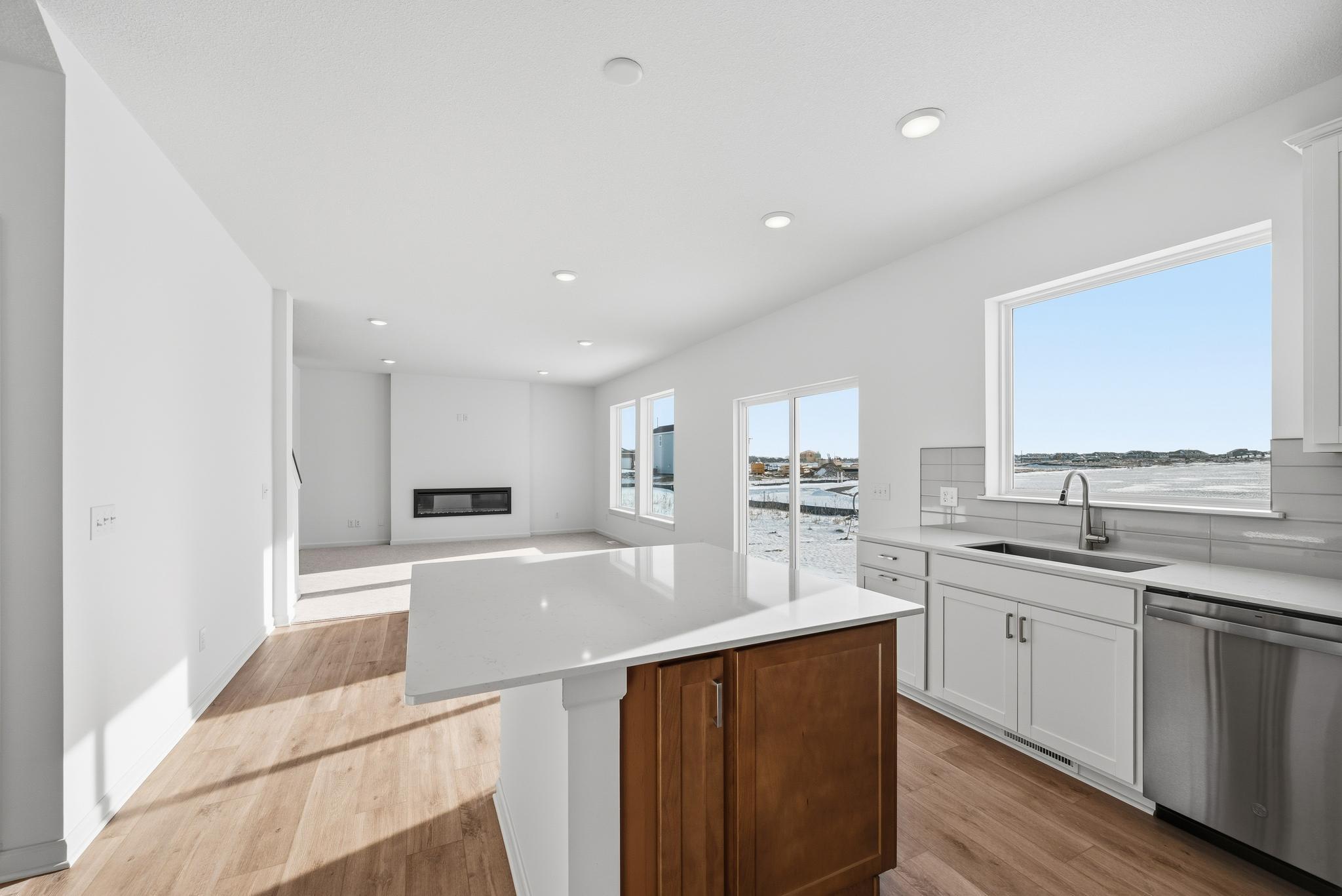 The kitchen combines style and functionality with white cabinetry, quartz countertops, and a spacious center island that offers additional prep space and seating. Images of similar home, interior selections differ.