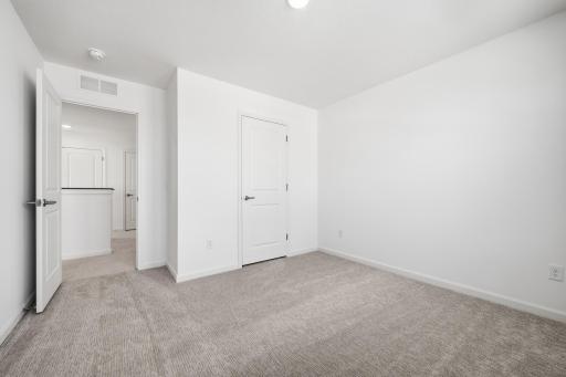 This secondary bedroom features a comfortable layout with well-placed windows, allowing natural light to brighten the space. Images of similar home, interior selections differ.