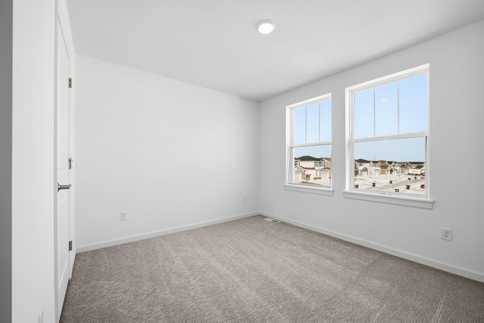 This secondary bedroom features a comfortable layout with well-placed windows, allowing natural light to brighten the space. Images of similar home, interior selections differ.