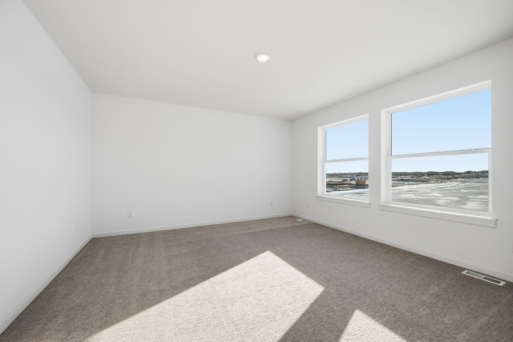 The primary bedroom serves as a comfortable retreat with generous space and large windows that fill the room with natural light. Images of similar home, interior selections differ.
