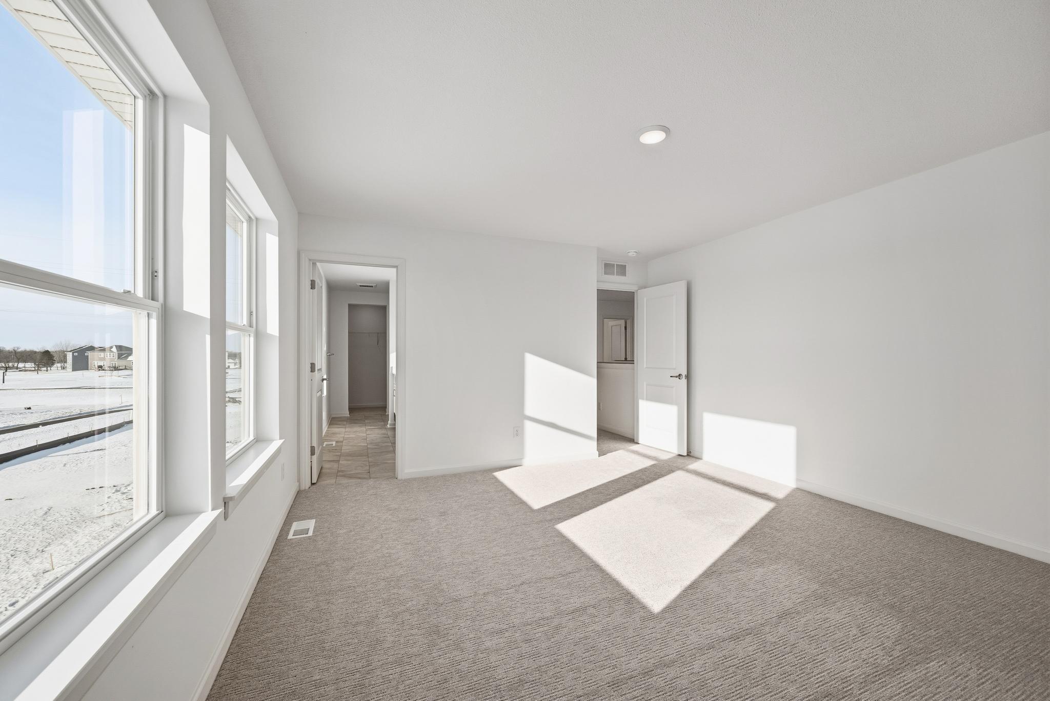 The primary bedroom serves as a comfortable retreat with generous space and large windows that fill the room with natural light. Images of similar home, interior selections differ.