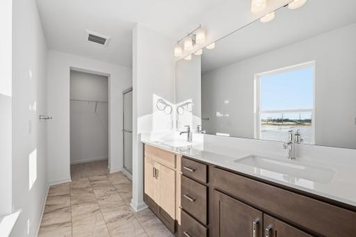 The primary bathroom features a dual-sink vanity with quartz countertops, ample cabinetry, and modern fixtures. Images of similar home, interior selections differ.