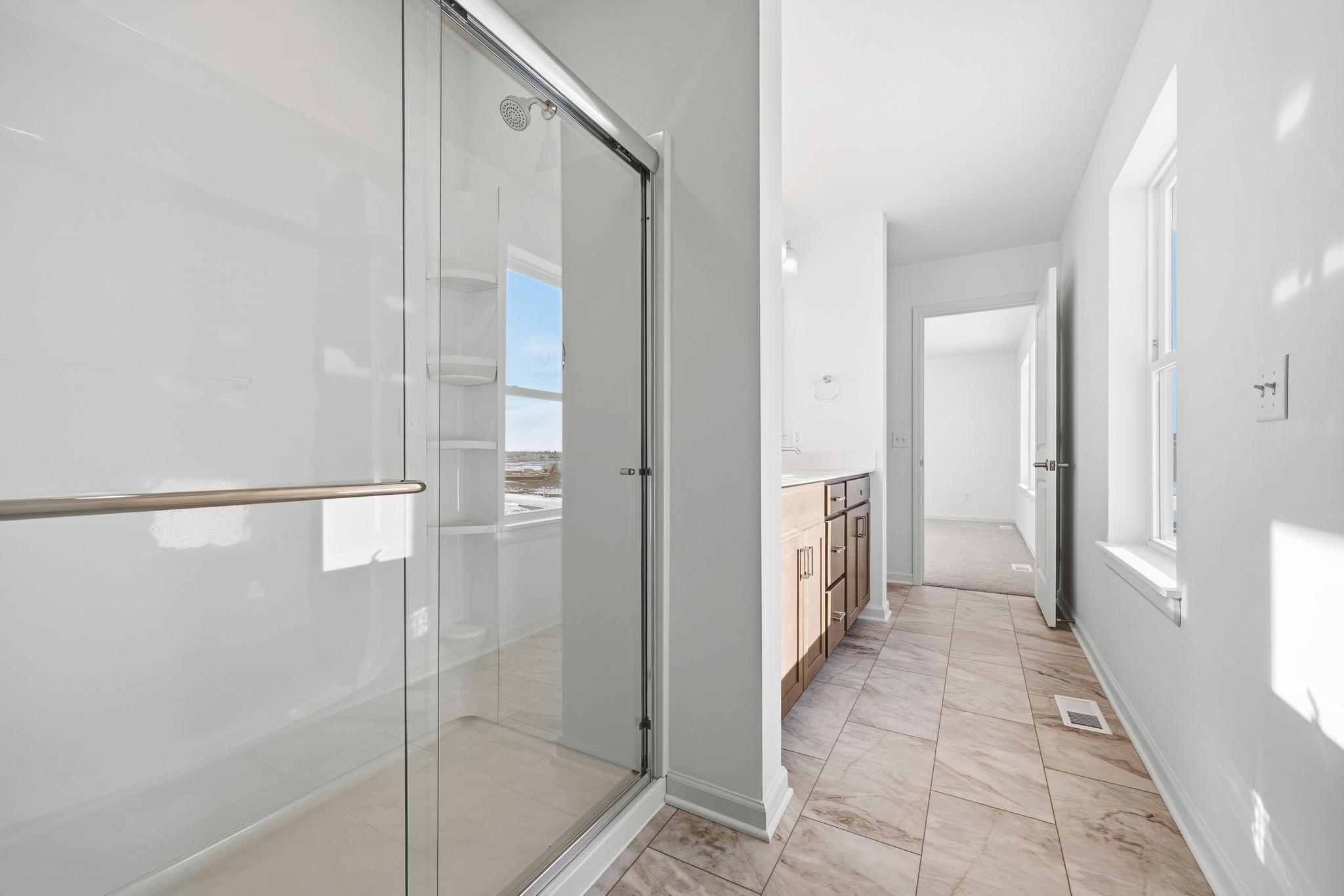 The primary bathroom features a dual-sink vanity with quartz countertops, ample cabinetry, and modern fixtures. Images of similar home, interior selections differ.