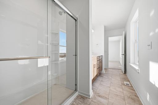 The primary bathroom features a dual-sink vanity with quartz countertops, ample cabinetry, and modern fixtures. Images of similar home, interior selections differ.