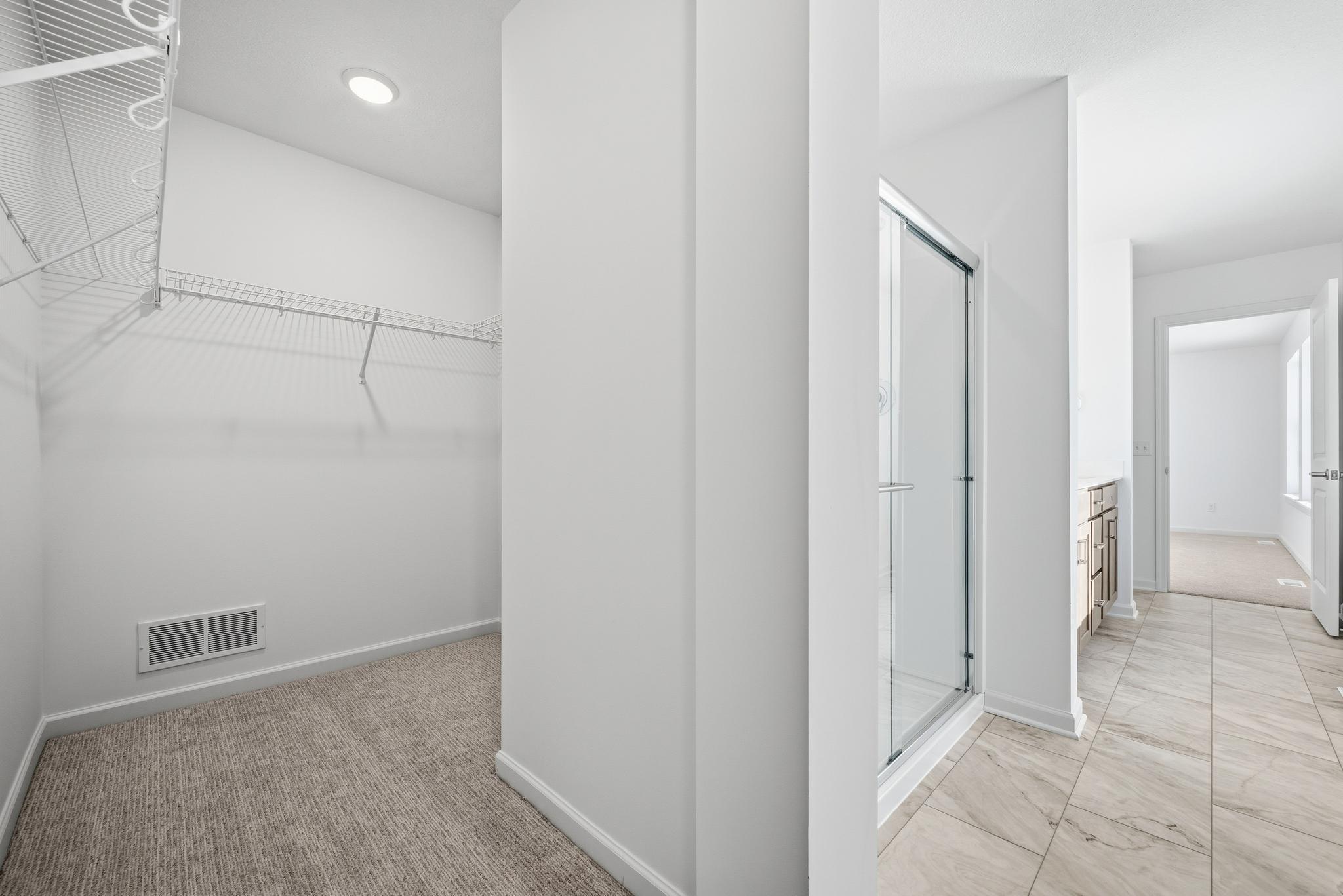 The primary bathroom features a dual-sink vanity with quartz countertops, ample cabinetry, and modern fixtures. Attached is a generous walk-in closet with ample room for all your clothes. Images of similar home, interior selections differ.