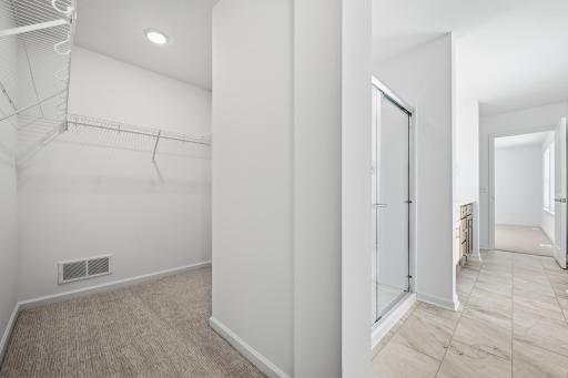 The primary bathroom features a dual-sink vanity with quartz countertops, ample cabinetry, and modern fixtures. Attached is a generous walk-in closet with ample room for all your clothes. Images of similar home, interior selections differ.
