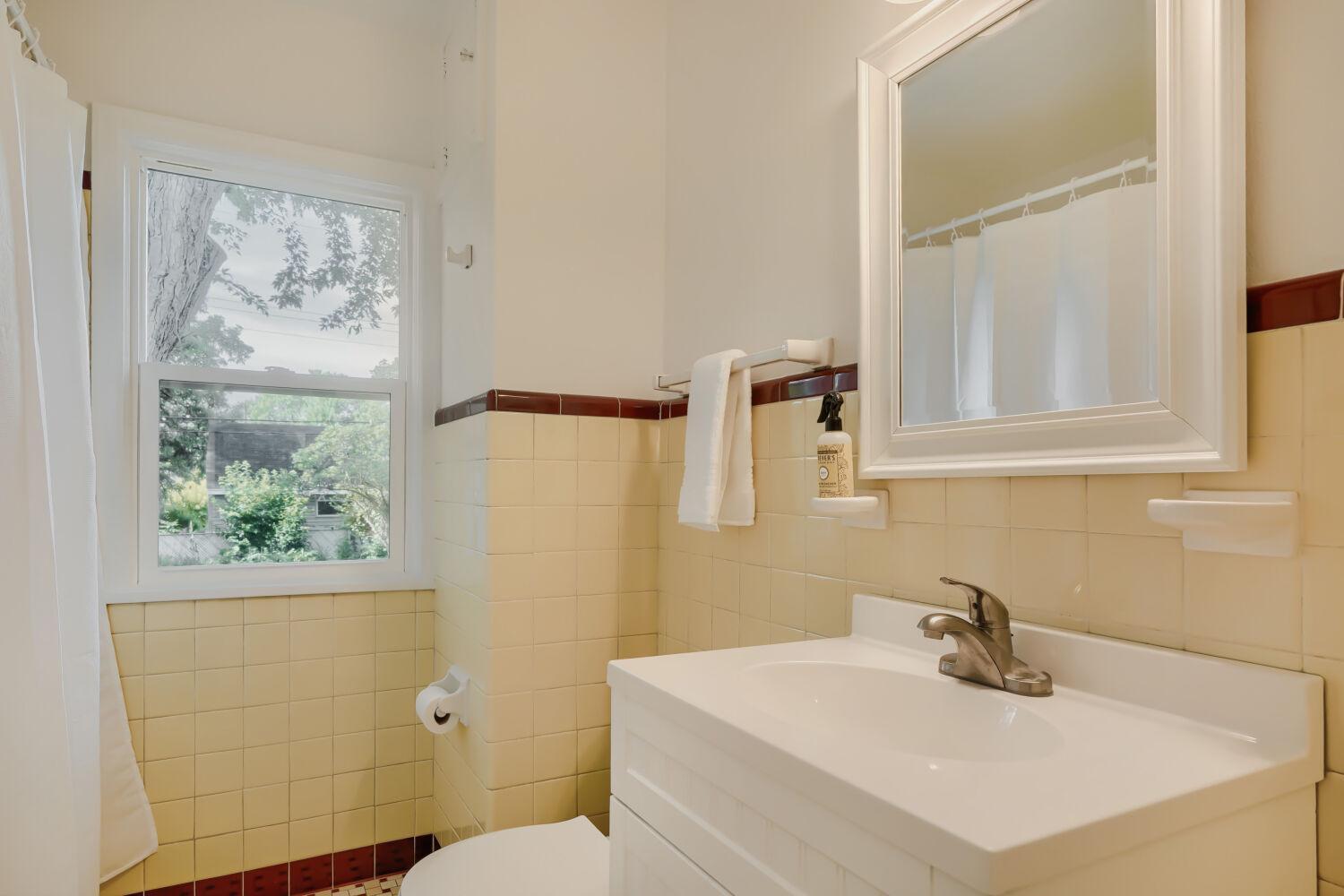 7711 Division St - Main floor bath features new fixtures, toilet, vanity, and a freshly glazed cast iron tub/shower.