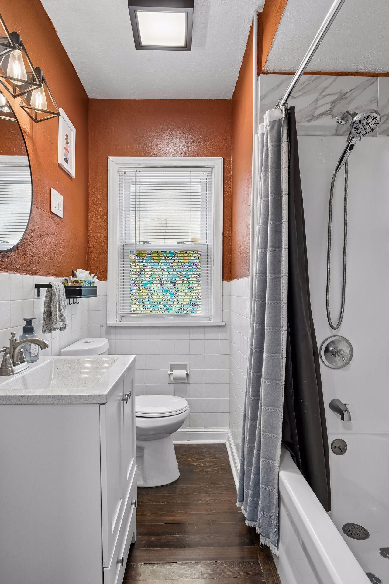 Fresh, bright, and functional. The main-level full bathroom features an updated vanity, modern fixtures, a tub and shower combination, and a large window that fills the space with natural light while maintaining privacy.