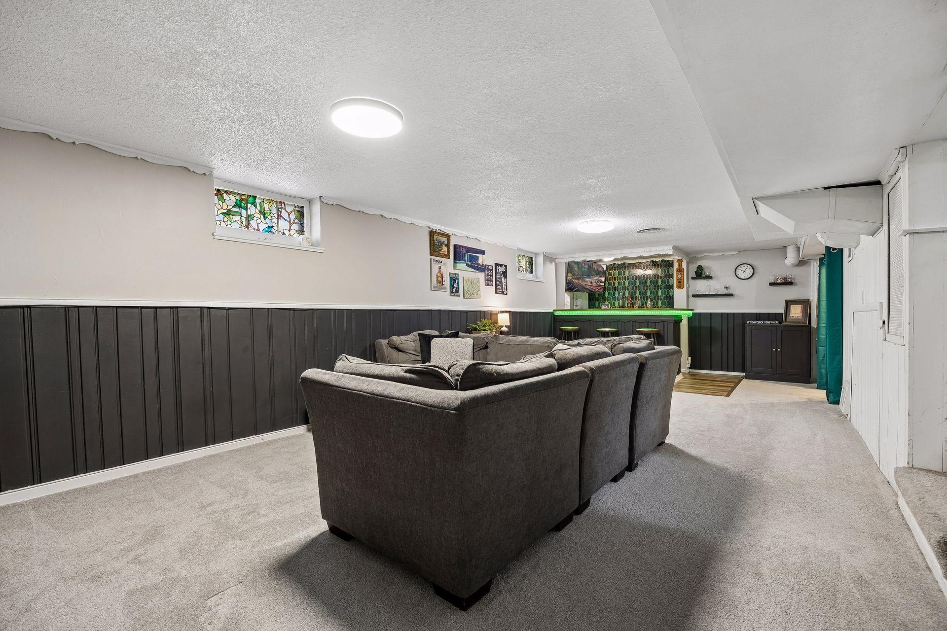 A spacious lower-level family room offers the perfect place to relax, host movie nights, or gather with family and friends, with easy access to the adjoining bar area.