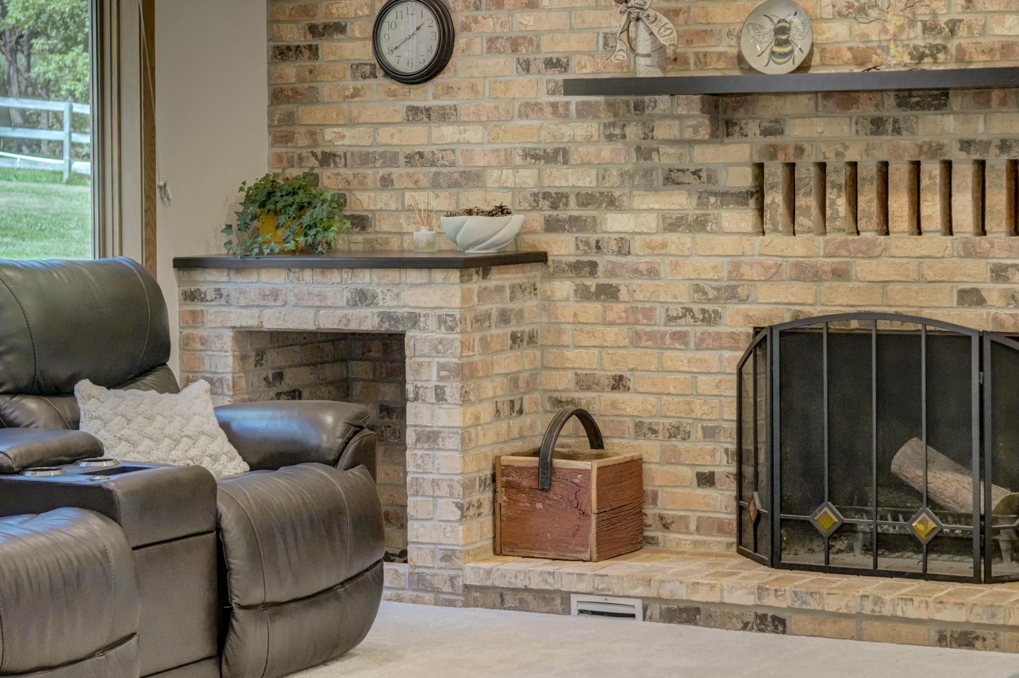 The brick wood-burning fireplace serves as a stunning focal point, complete with built-in wood storage for effortless fireside living