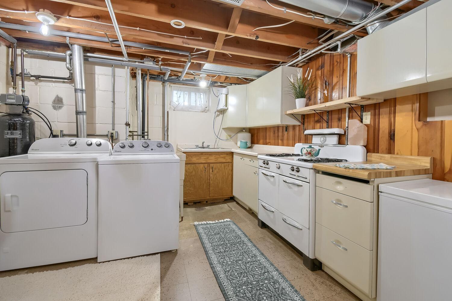 Say what!? Check out this lower level kitchenette with the laundry area! Gas stove, deep freezer, full refrigerator. (You HAVE to come open the cabinets for a cool surprise!)
