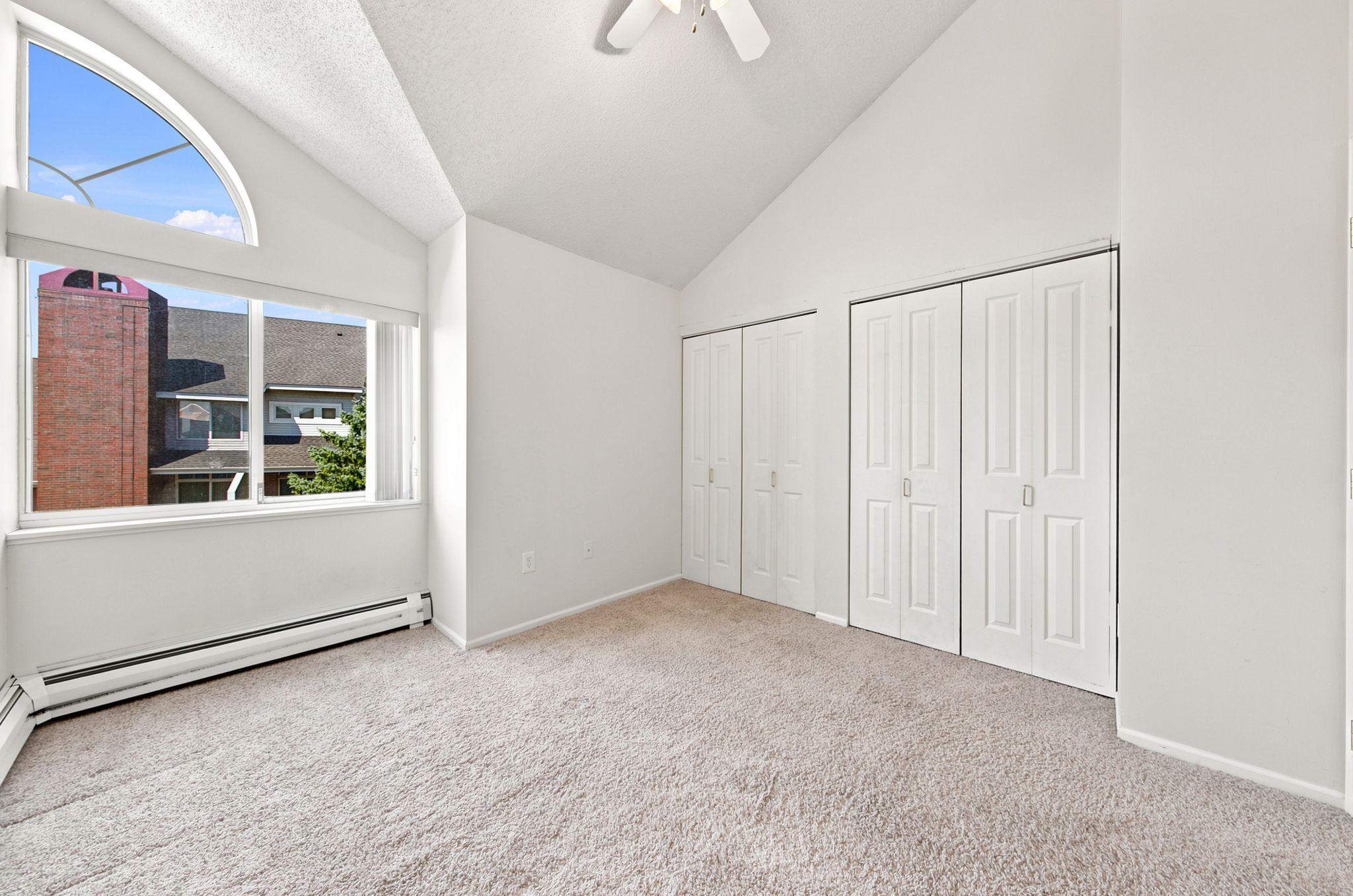 Bedroom with vaulted ceilings, large windows and ceiling fan