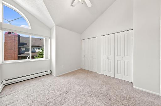 Bedroom with vaulted ceilings, large windows and ceiling fan