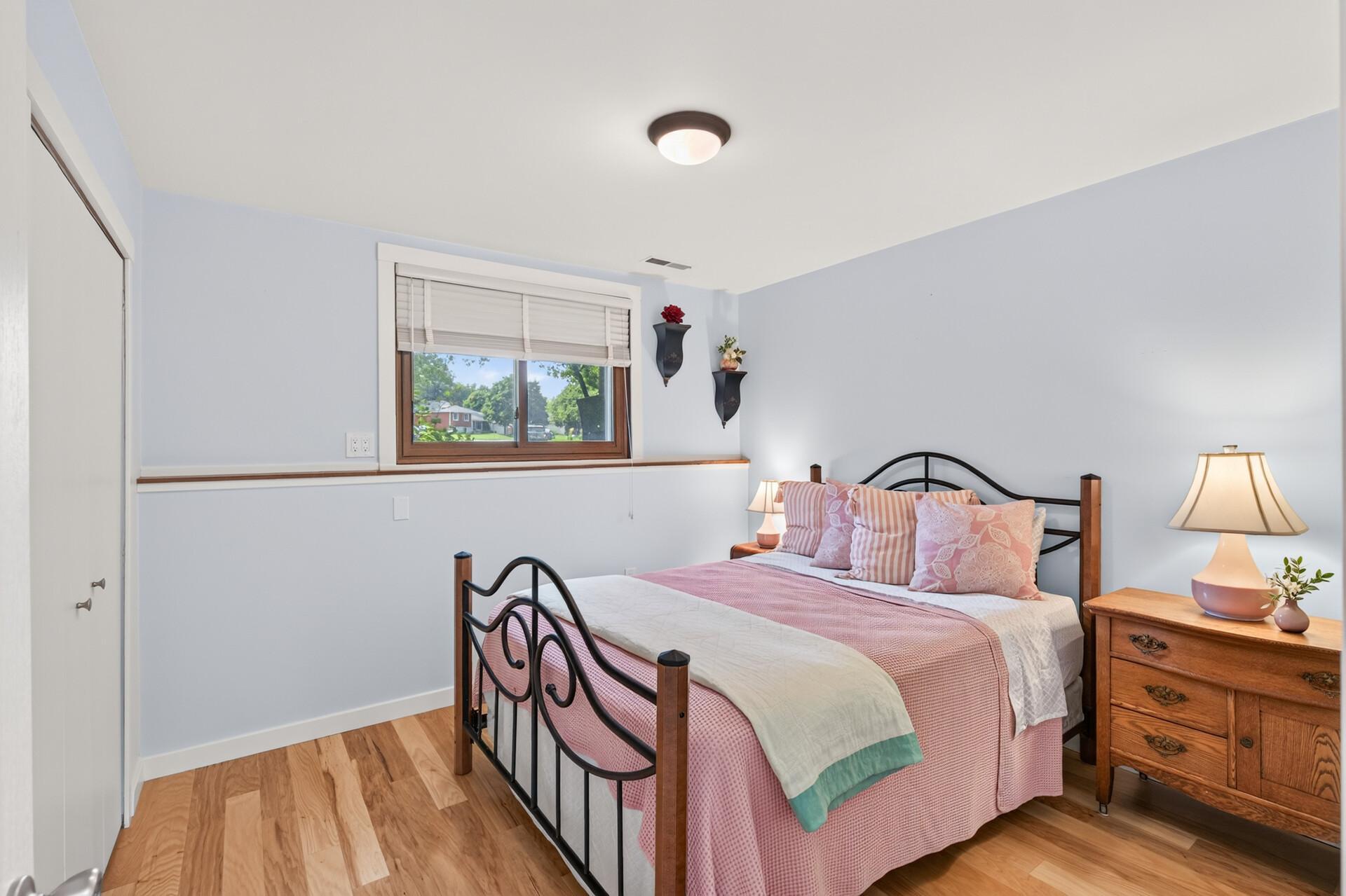 Comfortable fifth bedroom with hardwood flooring and a calm, welcoming atmosphere.