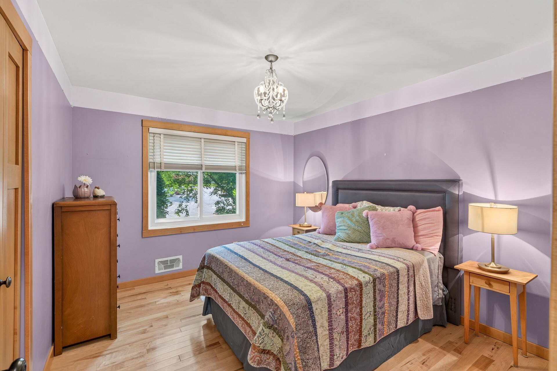 Bright upper-level bedroom with warm hardwood flooring and space to make your own.
