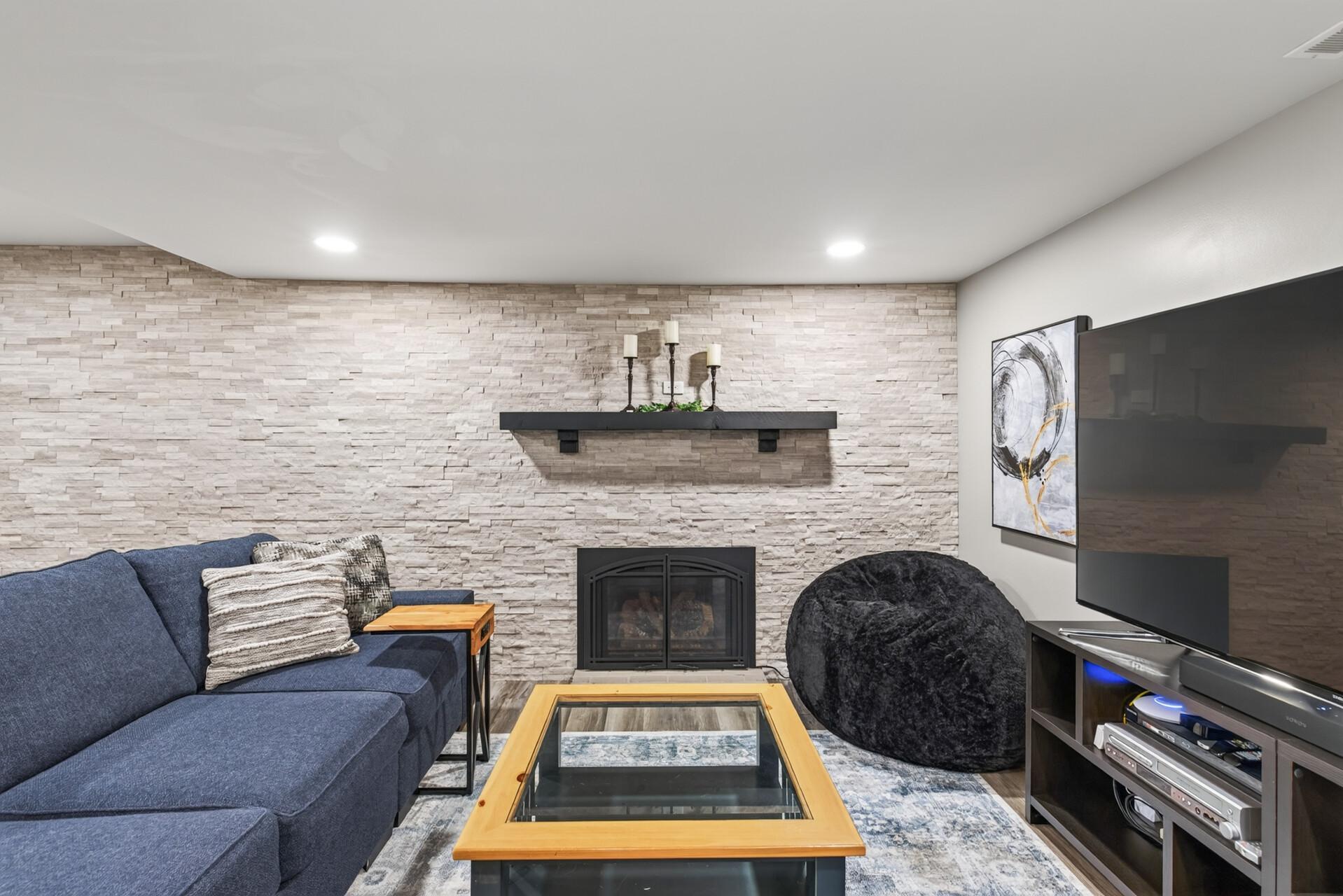 A gas-burning stone-and-brick fireplace creates a warm focal point in the lower-level living room.