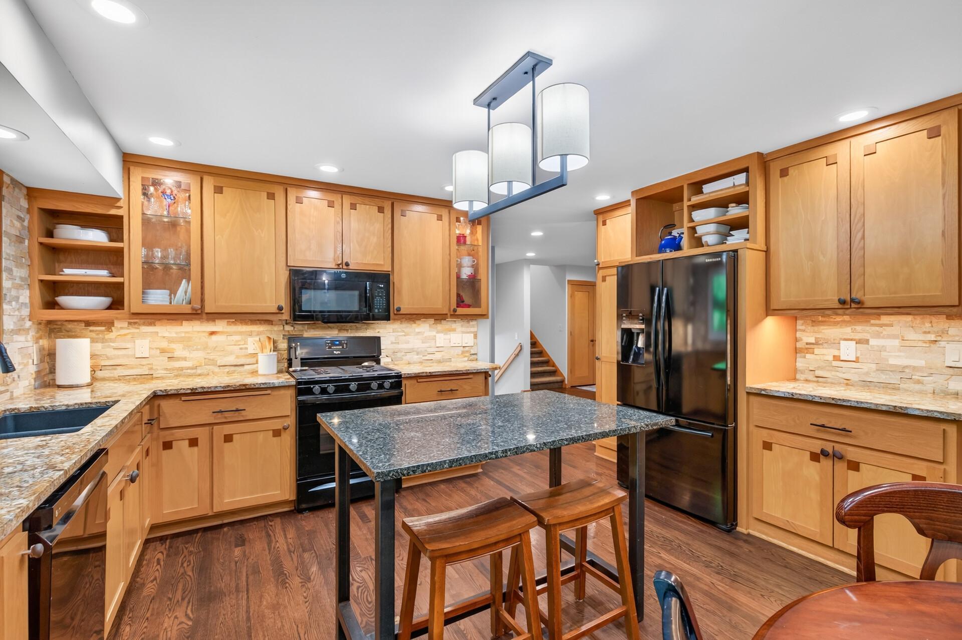 Warm maple cabinetry, granite countertops & island with stone backsplash and convenient undercounter lighting!