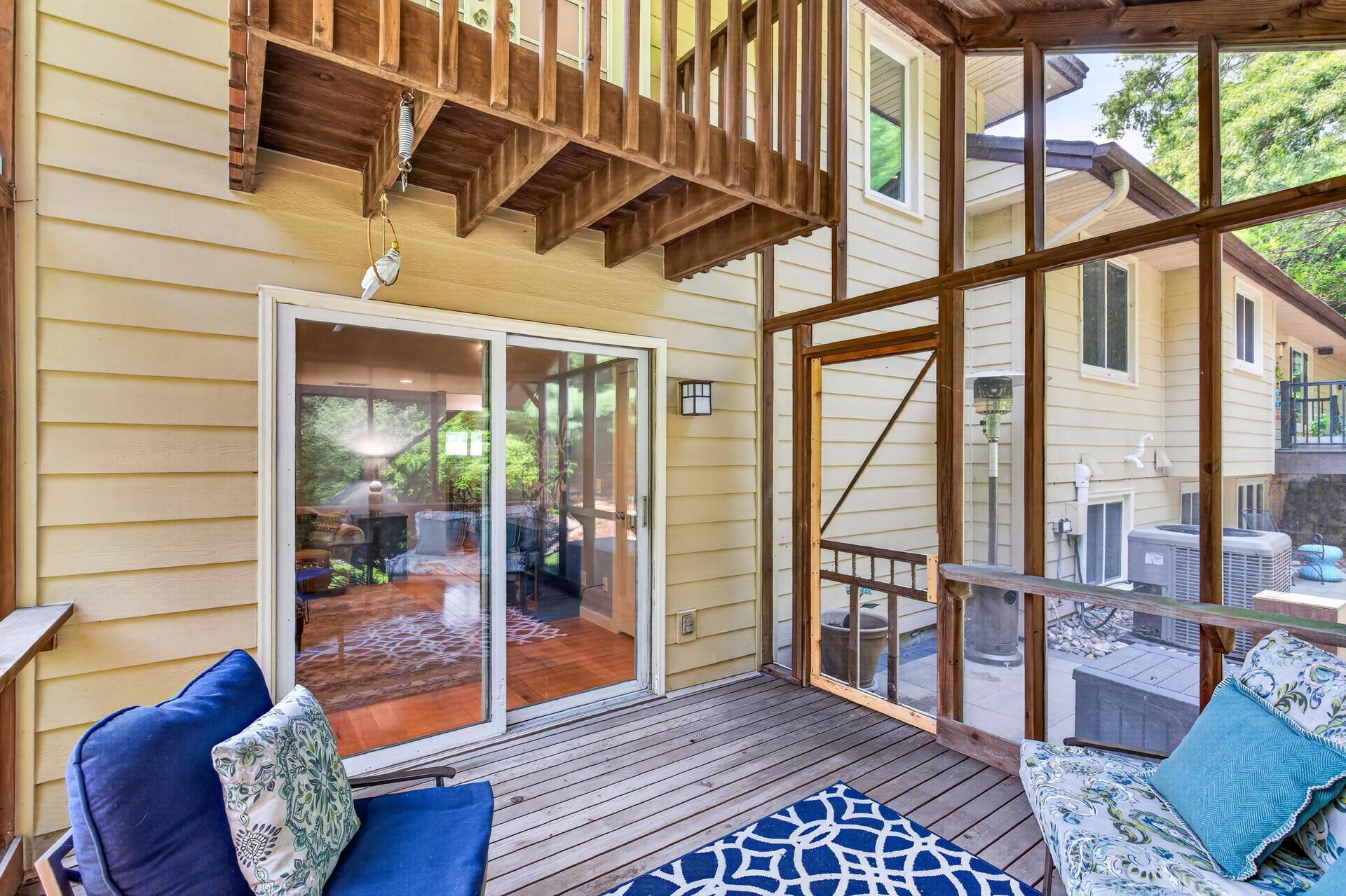 Surrounded by leafy views, the porch feels like a peaceful retreat tucked among the trees. The primary bedroom balcony is seen above.