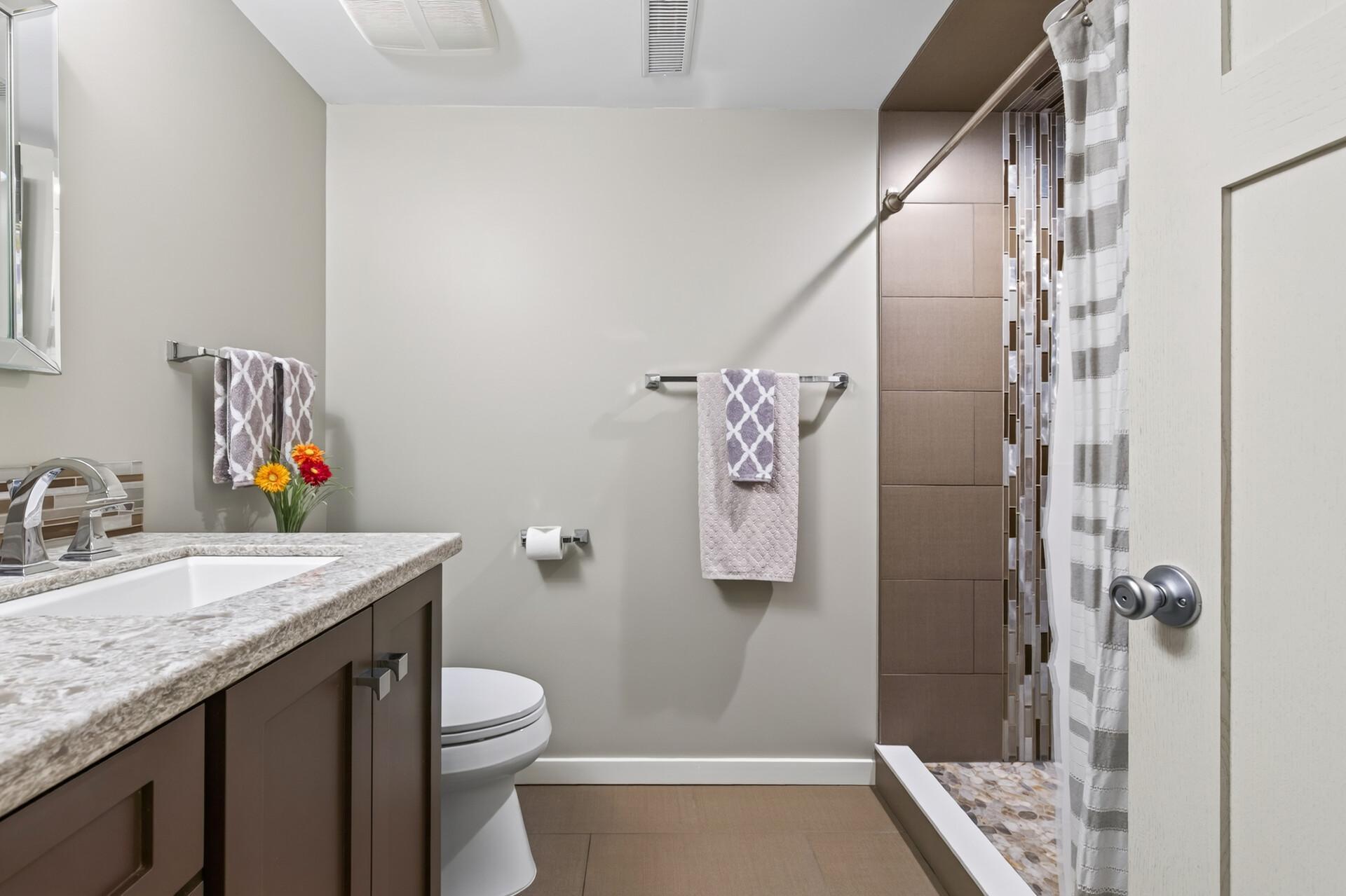 Updated third-level bath featuring a stylish vanity, contemporary finishes, and a beautifully tiled shower.