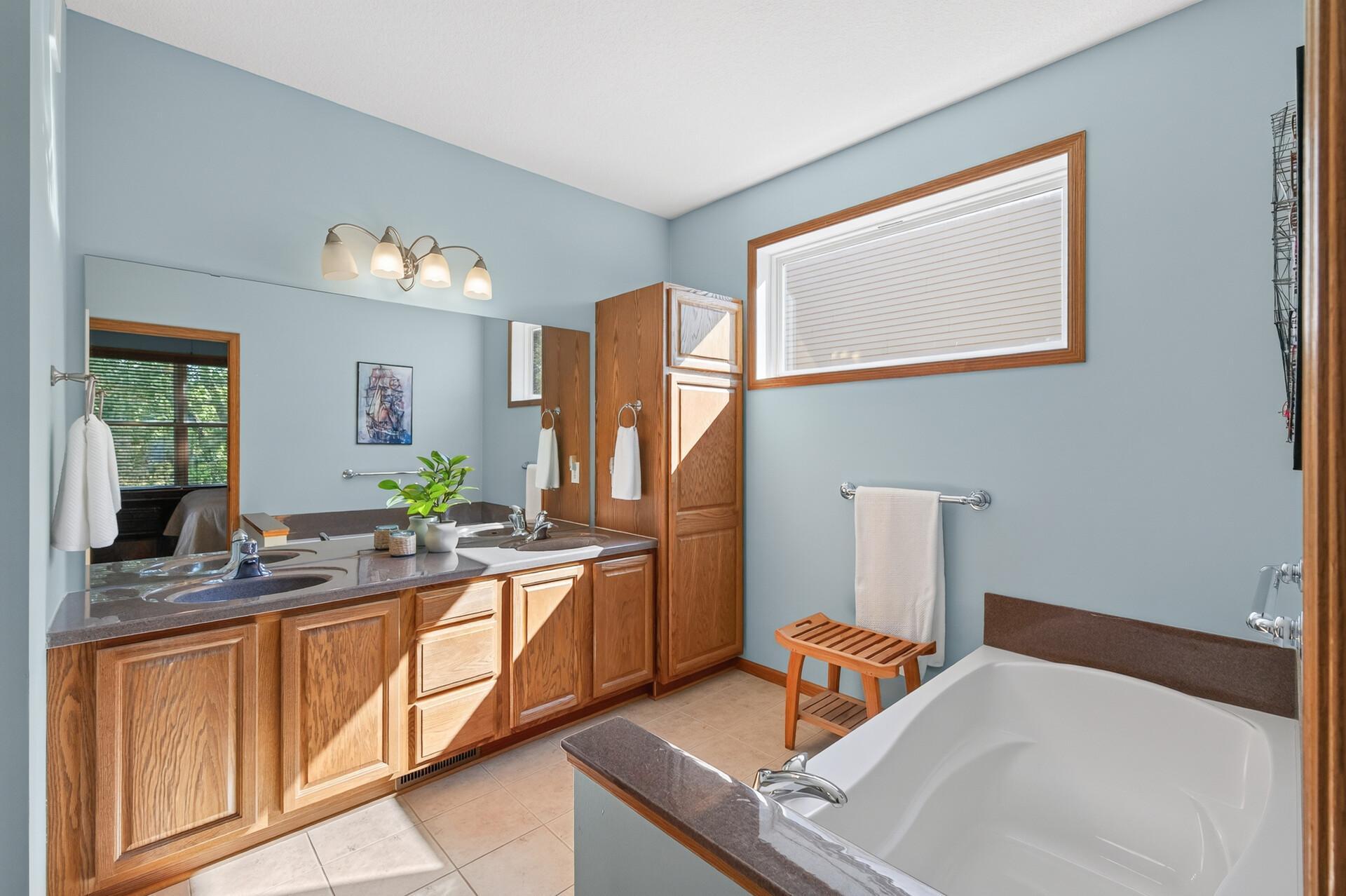 Huge primary bathroom with dual sinks, soaking tub and separate shower. Look at the light from this privacy window!