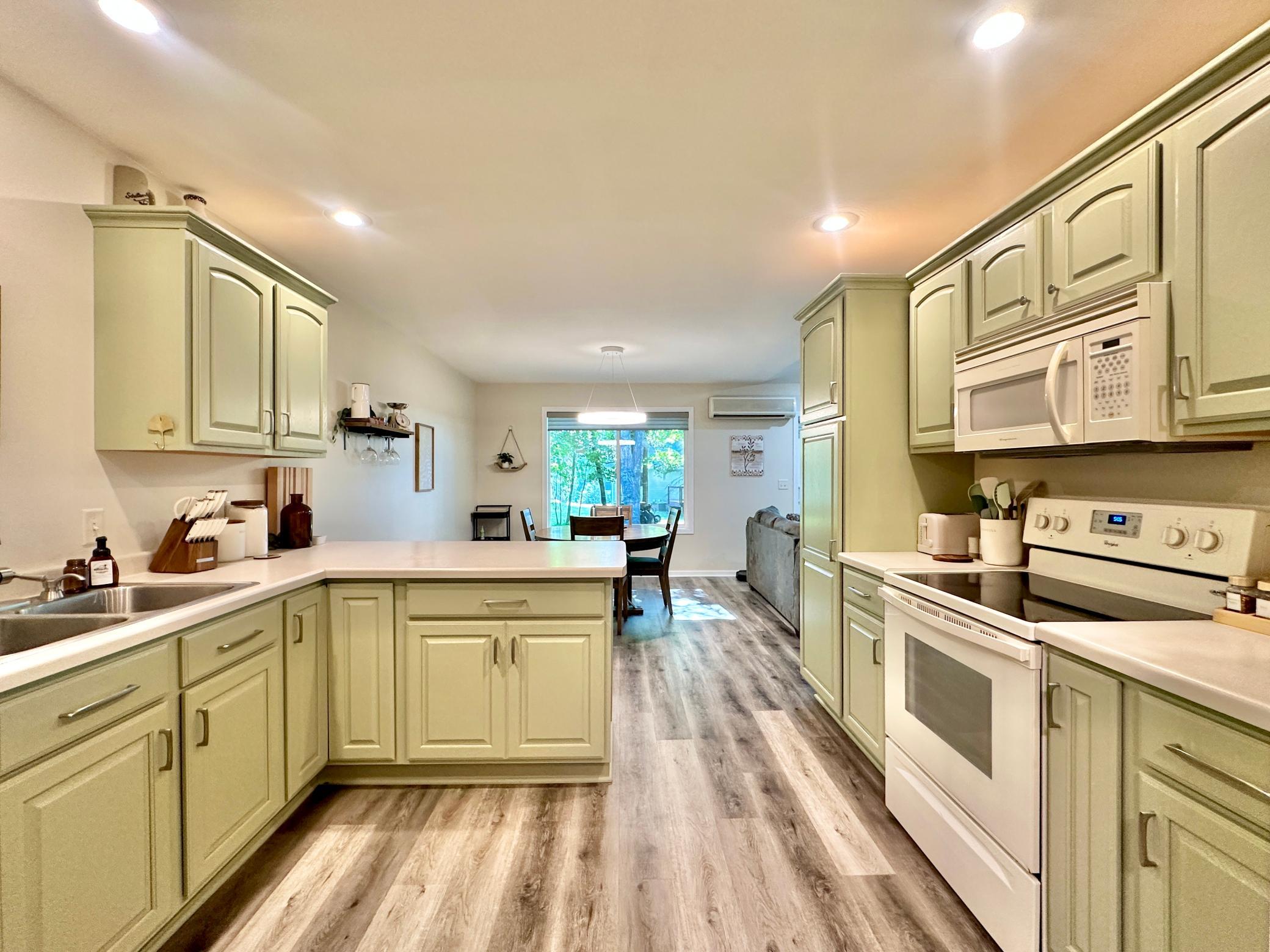 LVP flooring for easy clean ups, white appliances and a light olive cabinetry.