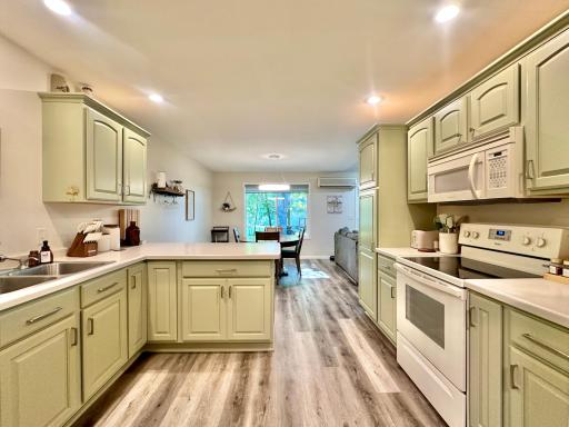 LVP flooring for easy clean ups, white appliances and a light olive cabinetry.