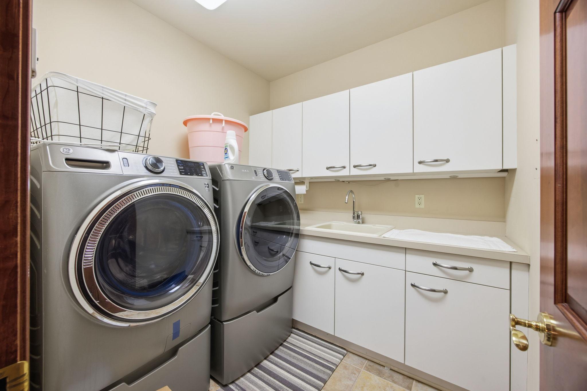 Conveniently located near the four lower-level bedrooms, the laundry room offers plenty of cabinet space and a utility sink