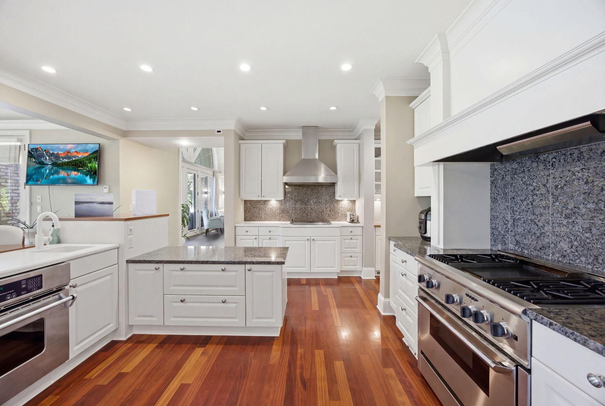 Warm wood floors and crisp white cabinetry create a bright, inviting kitchen with room for everyone