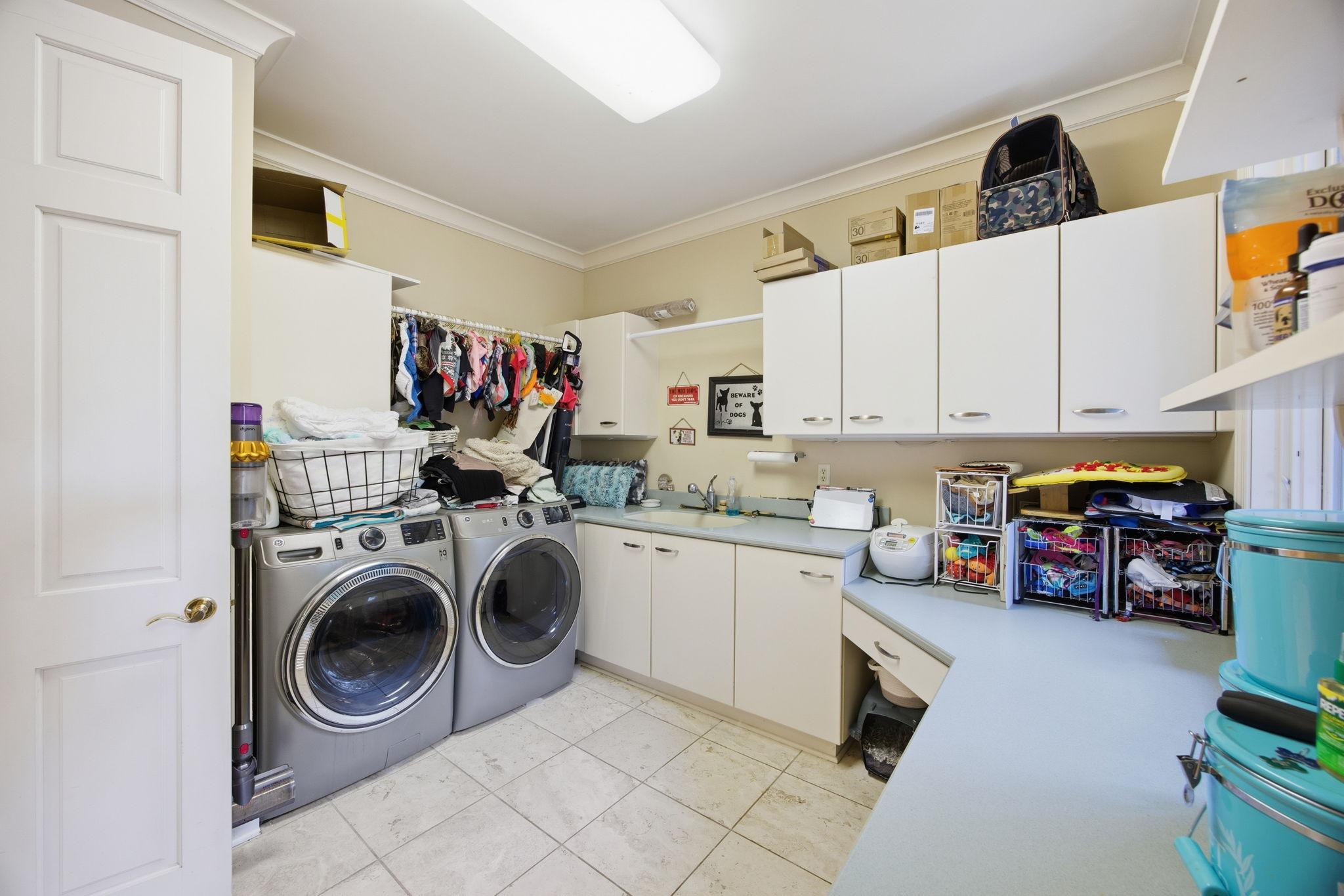 The dedicated laundry room includes abundant cabinetry, counter space, and a utility sink