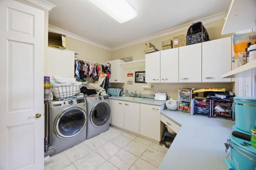 The dedicated laundry room includes abundant cabinetry, counter space, and a utility sink