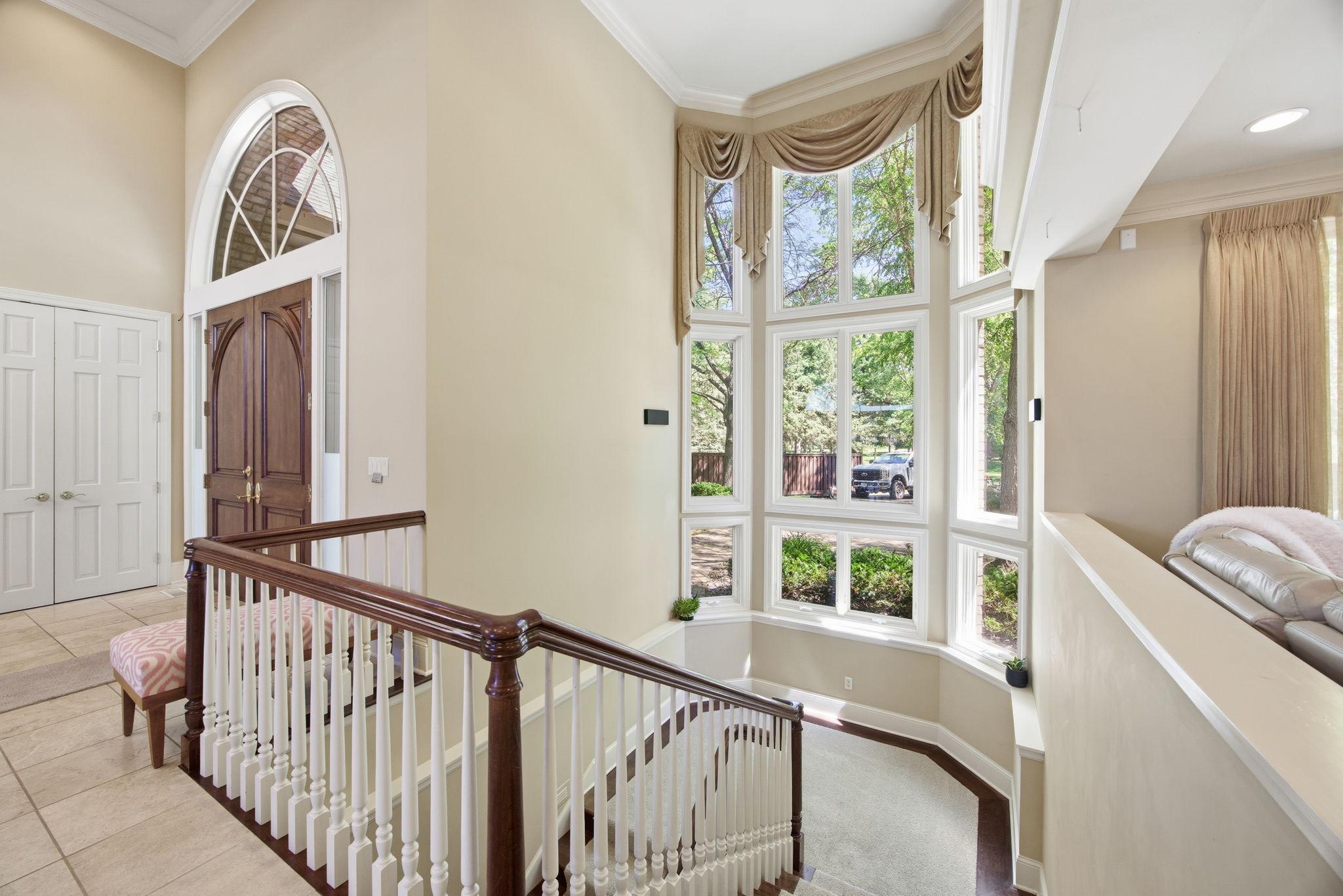 The staircase to the lower level is beautifully complemented by two stories of windows, filling the space with natural light