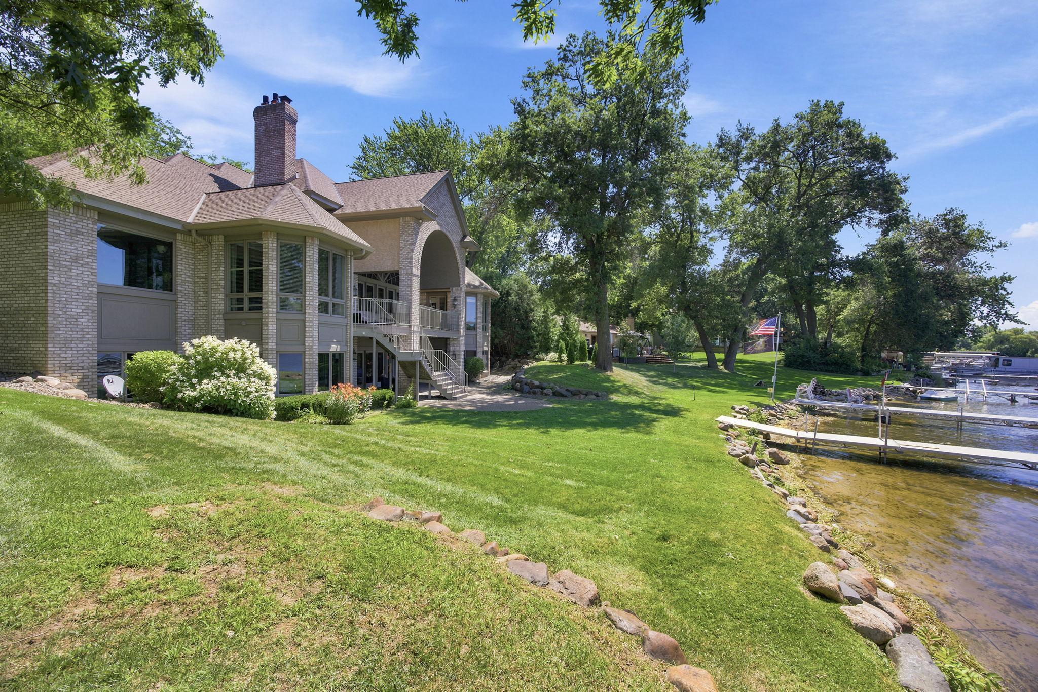 Beautiful brickwork, mature trees, and a broad green lawn frame the home along the water's edge