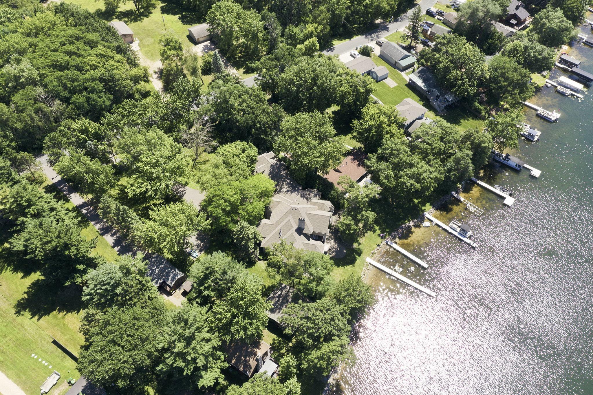 From above, the home sits beneath a canopy of trees with its lawn and dock opening directly to the water
