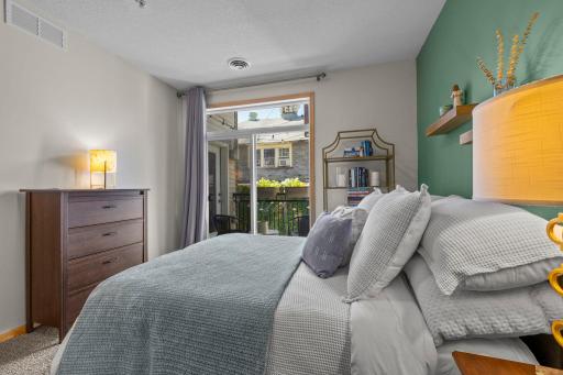 Primary suite bathed in natural light from the private balcony door