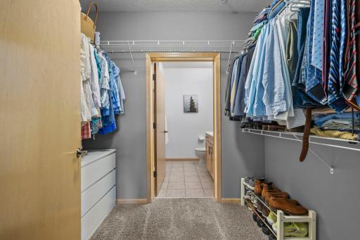 Walk-in closet with built-in shelving, leading to the en-suite bath