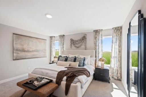 The large primary bedroom has an abundance of space and natural light. Photo of model home, color and finishes will vary.