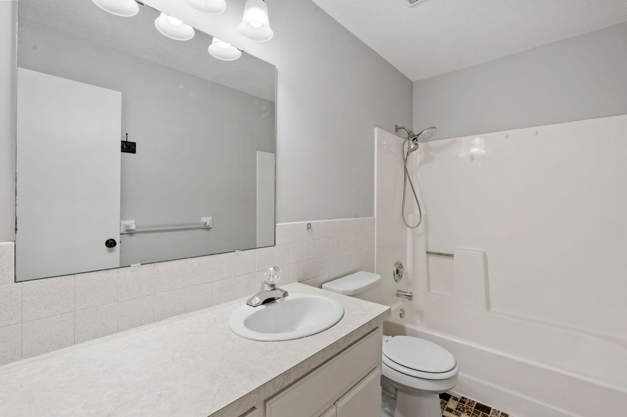 Full bathroom with vanity and tub/shower combination.
