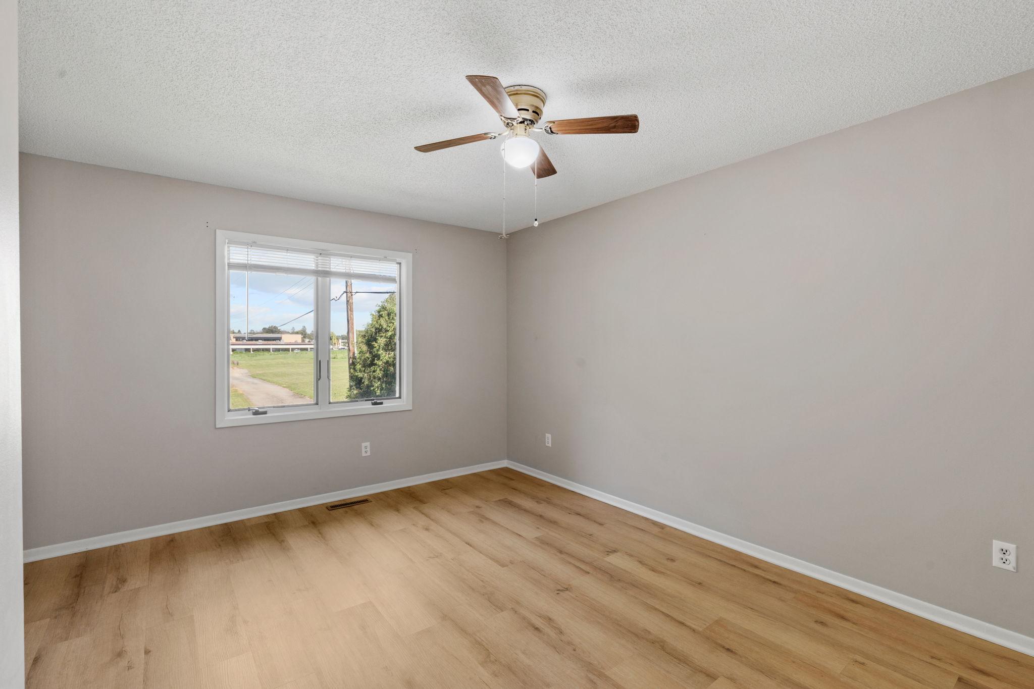 Bedroom with fresh paint, updated flooring, and a large window.