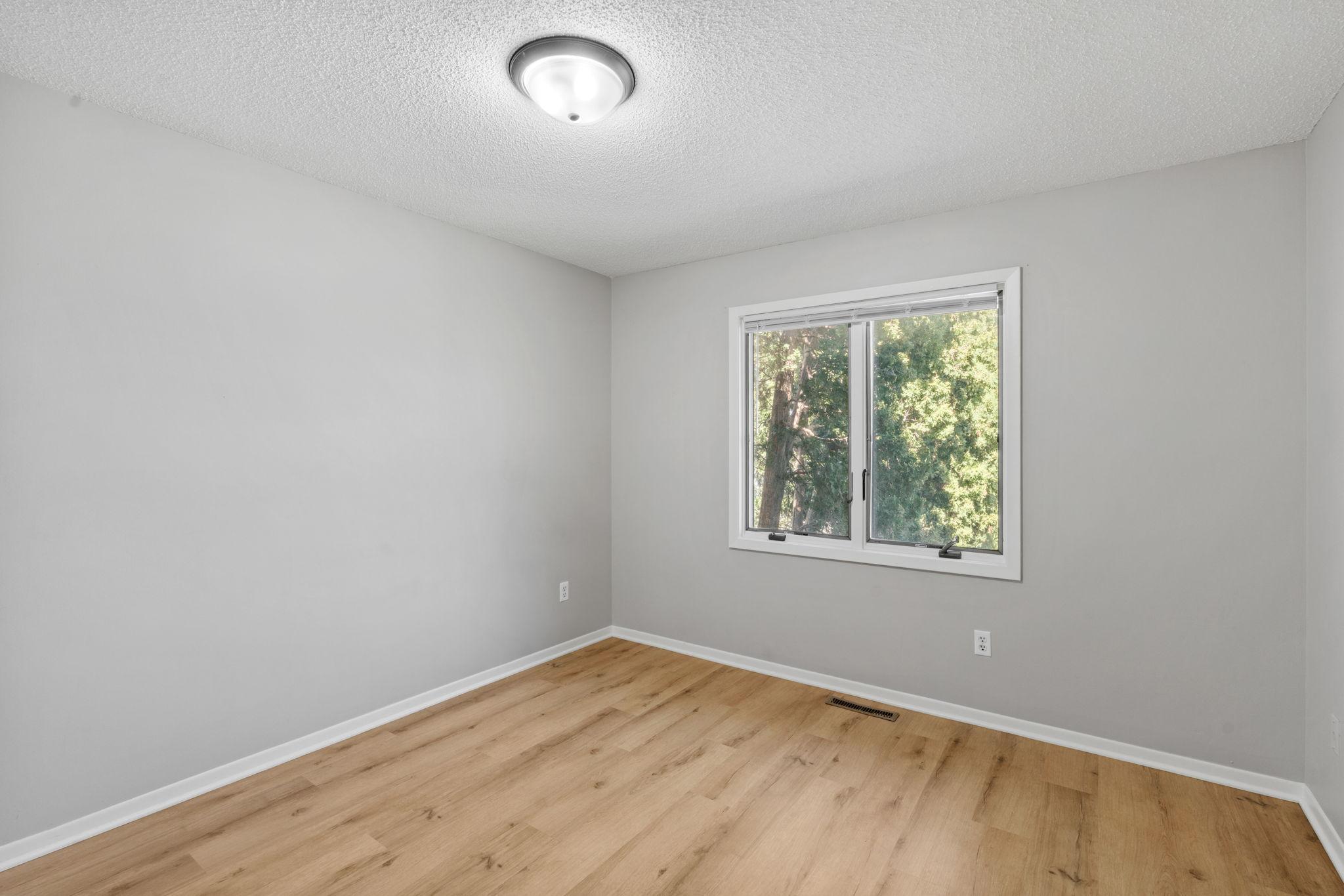 Secondary bedroom with updated flooring and backyard-facing window.