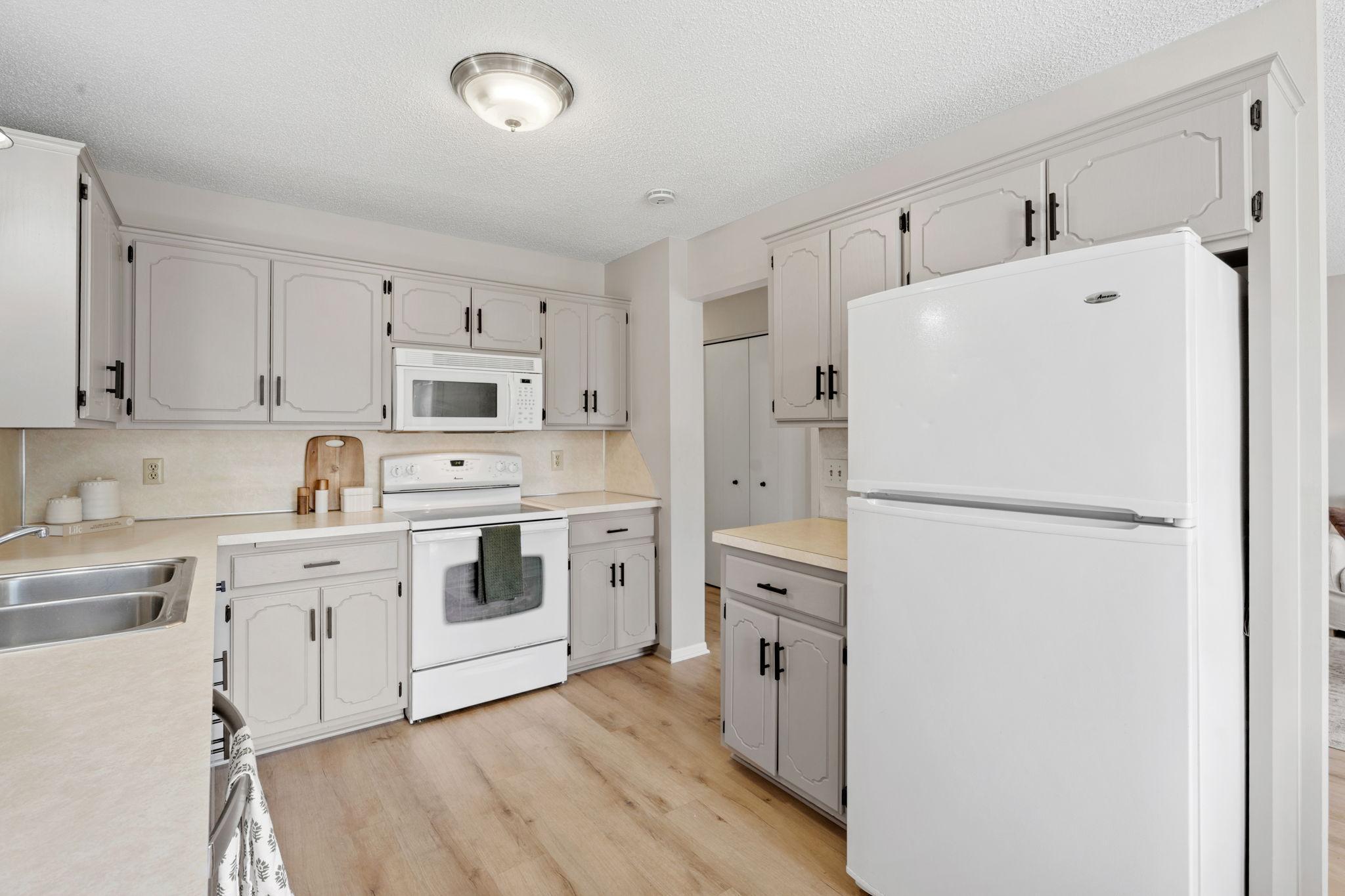 Additional view of the kitchen with white appliances and generous storage.