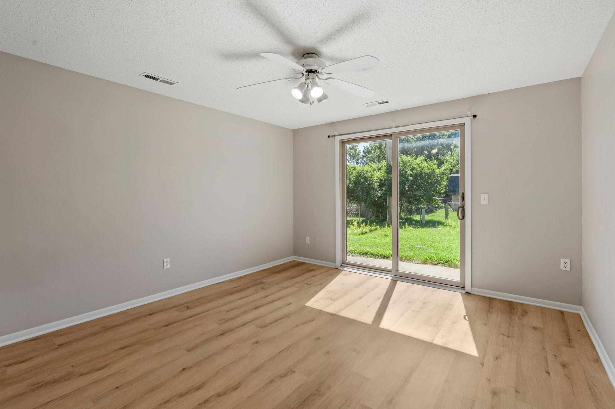 Primary bedroom with updated white oak flooring and sliding glass door to the backyard.