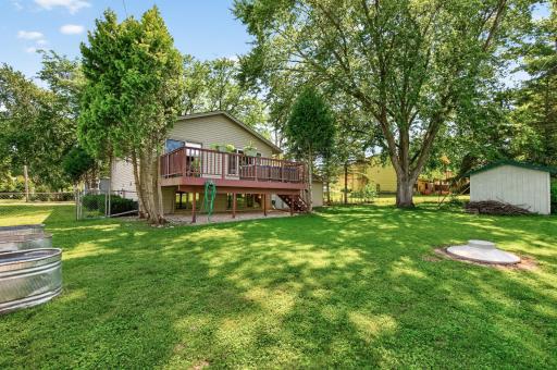 Enjoy the fully fenced backyard featuring mature trees, a spacious lawn, elevated metal planting beds, and plenty of room for gardening, entertaining, or outdoor activities