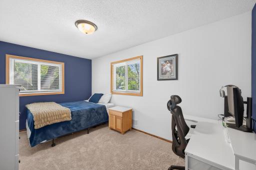 Upper level guest bedroom with newer windows and spacious area for furniture and a desk.