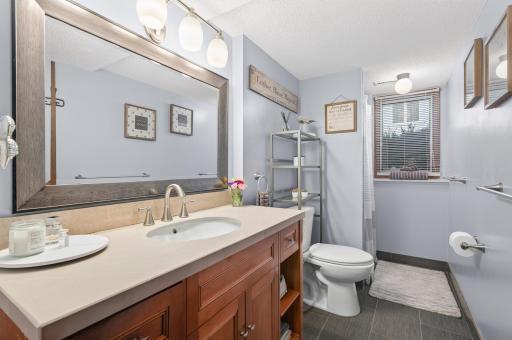 An updated full bathroom features a spacious vanity, modern fixtures, and a window that fills the space with natural light.
