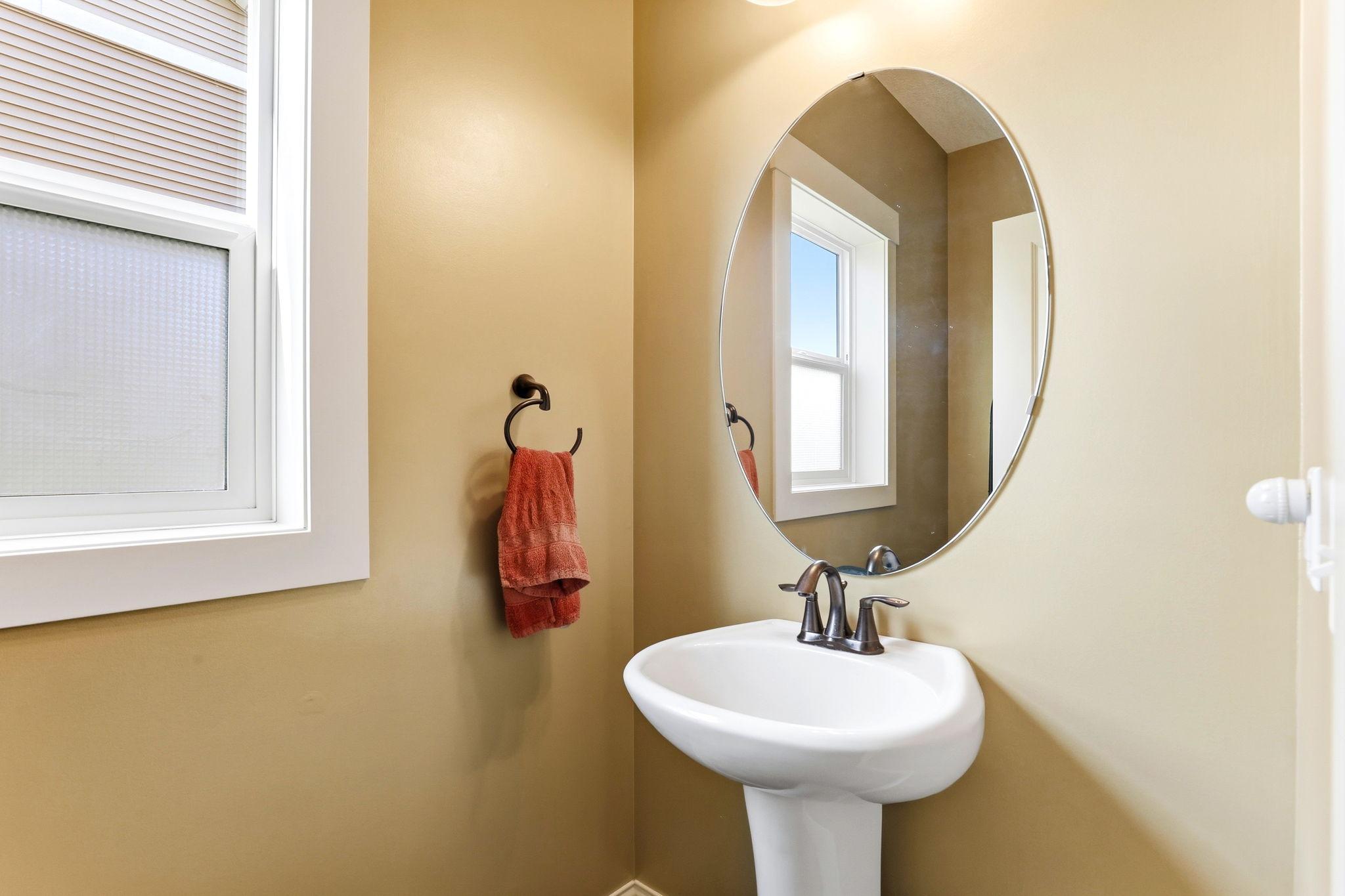 Mudroom area complete with convenient half bath featuring a pedestal sink and oval mirror.